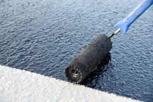 A contractor applying a sealant for moisture protection to a industrial floor surface